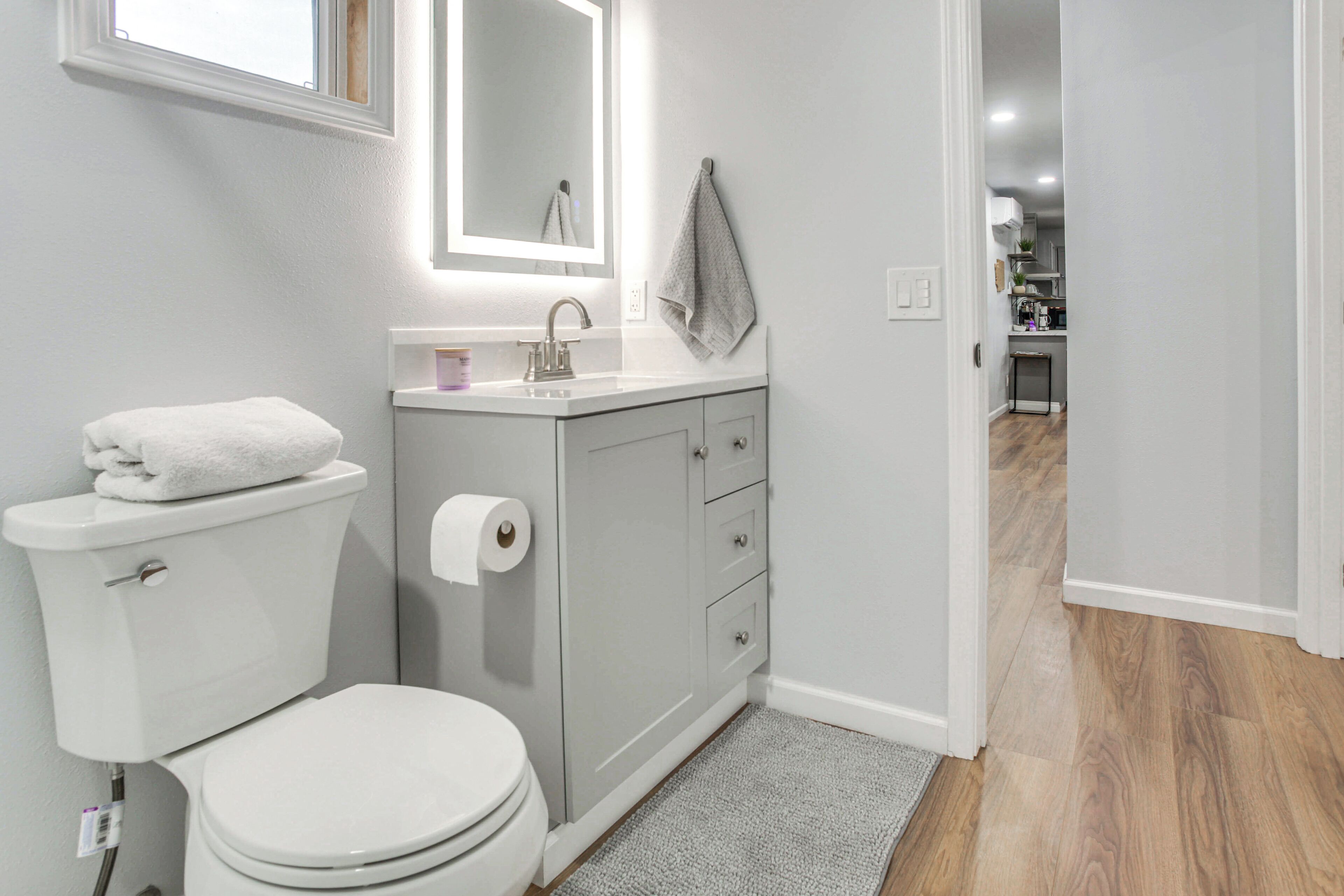 Een moderne badkamer met toilet, wastafel en spiegel.
