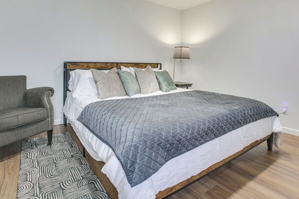 Une chambre à coucher avec un lit, une chaise, une table de chevet et une lampe.