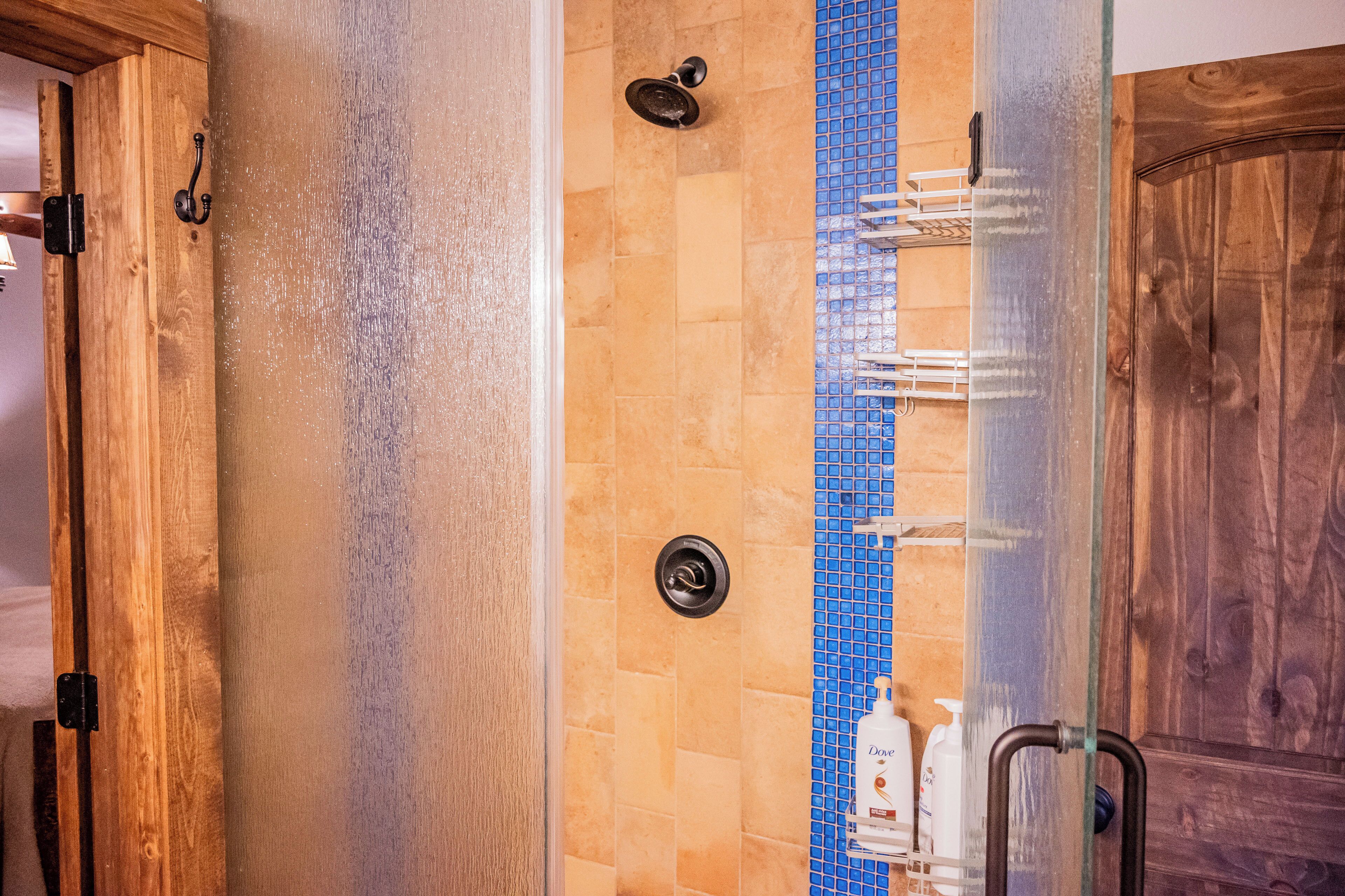 Une salle de bain avec une porte en bois, une douche avec une porte en verre et un mur recouvert de carreaux bleus.