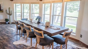 A spacious dining area with a long wooden table, six chairs, and large windows offering a view of the outdoors. - 2 Mi to Winter Park & Alto Lake! Family Retreat (Alto)