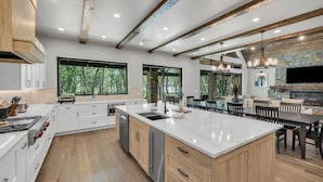 Une cuisine moderne dotée d’un grand îlot central, de meubles en bois et d’une cheminée en pierre.