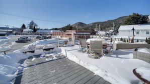 A snowy outdoor area with a wooden deck, seating, and a building labeled "WINE". - 3 Blocks to Lake George Village: Spacious Home! (Lake George)