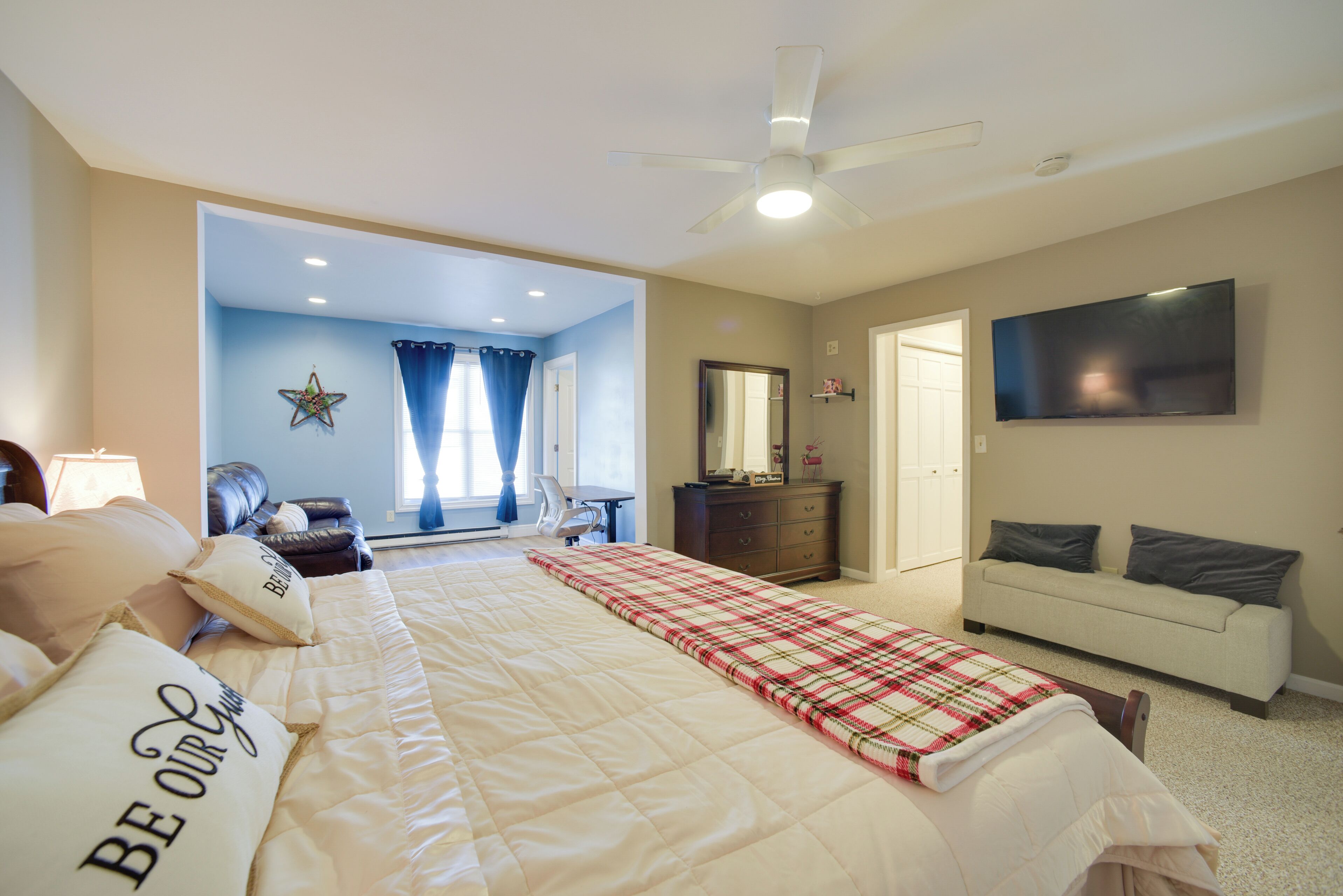 A bedroom with a bed, a dresser, a sofa, and a TV.