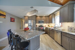 A modern kitchen with granite countertops, stainless steel appliances, and wooden cabinets. - 3 Blocks to Lake George Village: Spacious Home! (Lake George)