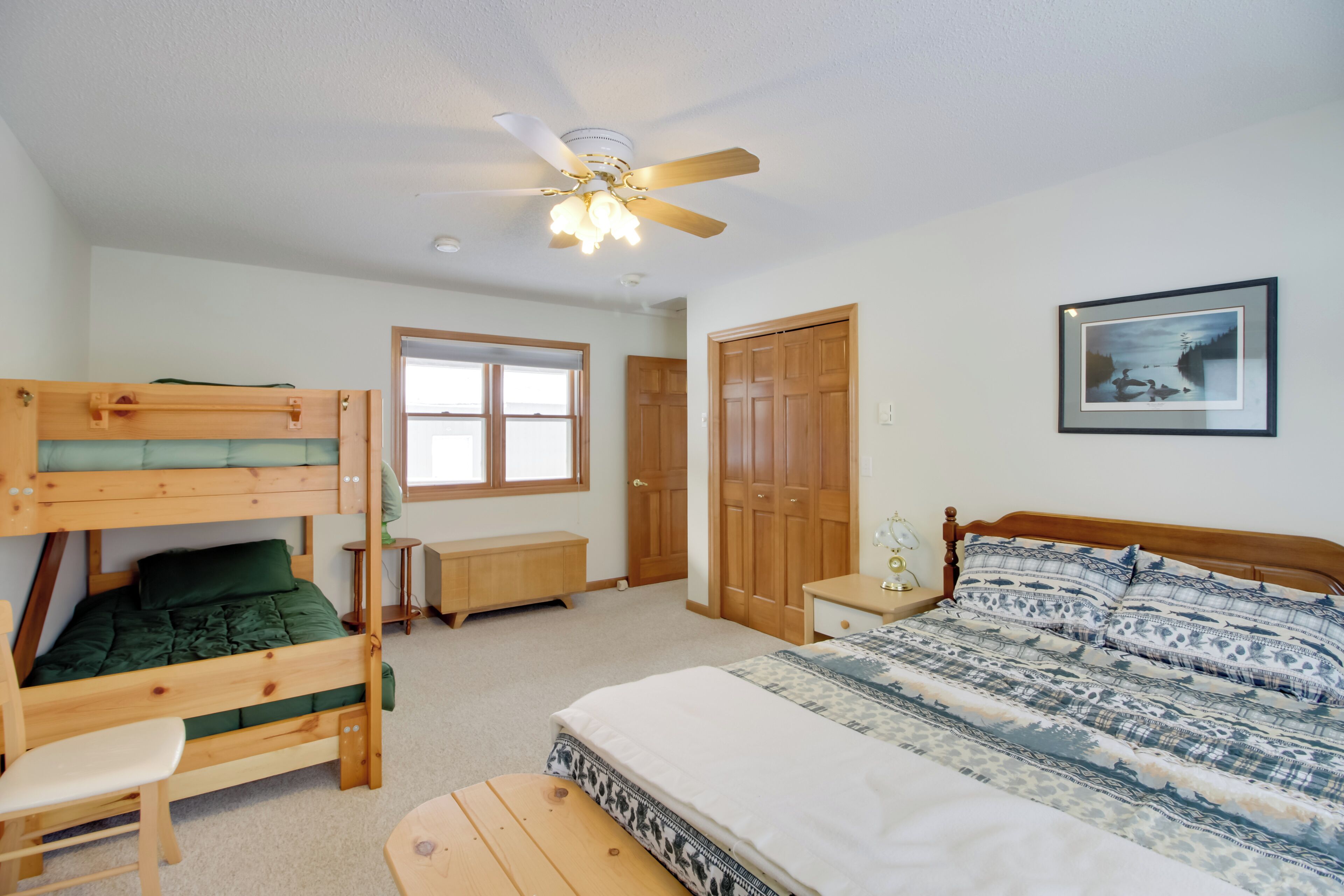 A bedroom with bunk beds, a single bed, a ceiling fan, a window, and a door.