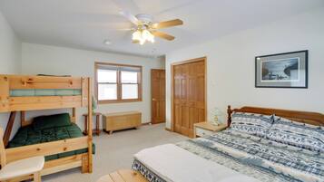 A bedroom with bunk beds, a single bed, a ceiling fan, a window, and a door.