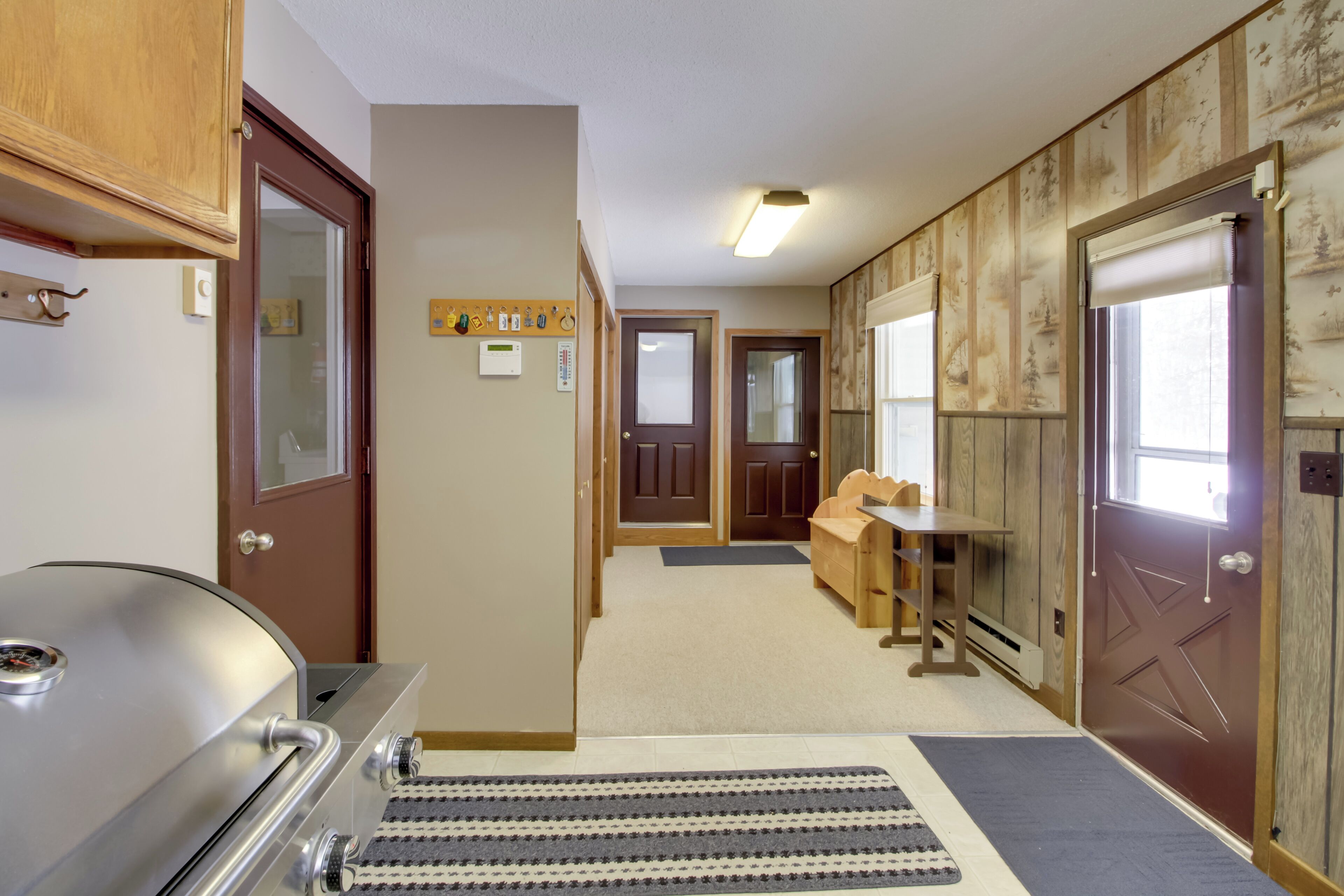 Una cocina compacta con una parrilla integrada, un banco de madera y una puerta que da a otra habitación.