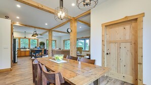 Un comedor espacioso con una mesa y sillas de madera, una araña y una gran puerta de madera.