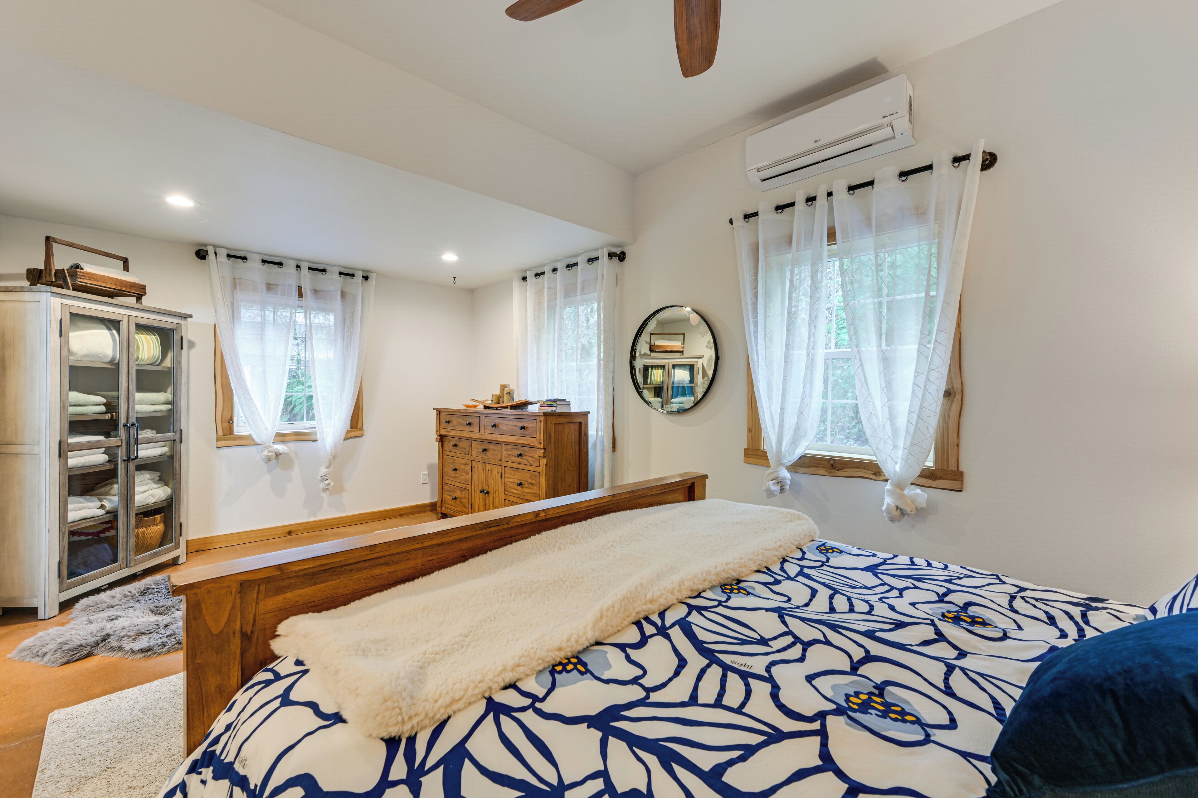 Un dormitorio con cama, cómoda de madera, armario y ventilador de techo.