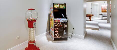 A hallway with a red gumball machine and a vintage arcade game.