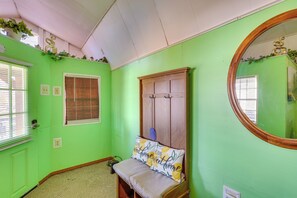 Ett rum med gröna väggar, en trägarderob, en bänk med en kudde och en spegel.