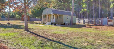 A single-story house with a porch, surrounded by a wooden fence and trees.