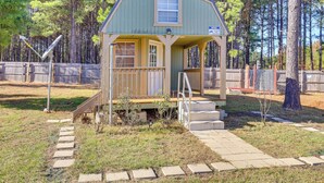 A small, single-story cabin with a porch and a 'G' on the gable. - Cozy Cabin in Overton Glamping Community w/ Perks! (Overton)
