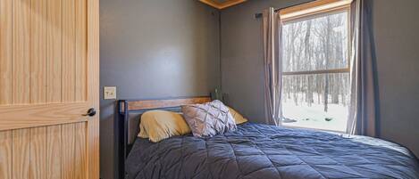 Une chambre à coucher avec un lit, une armoire en bois et une fenêtre avec des rideaux.
