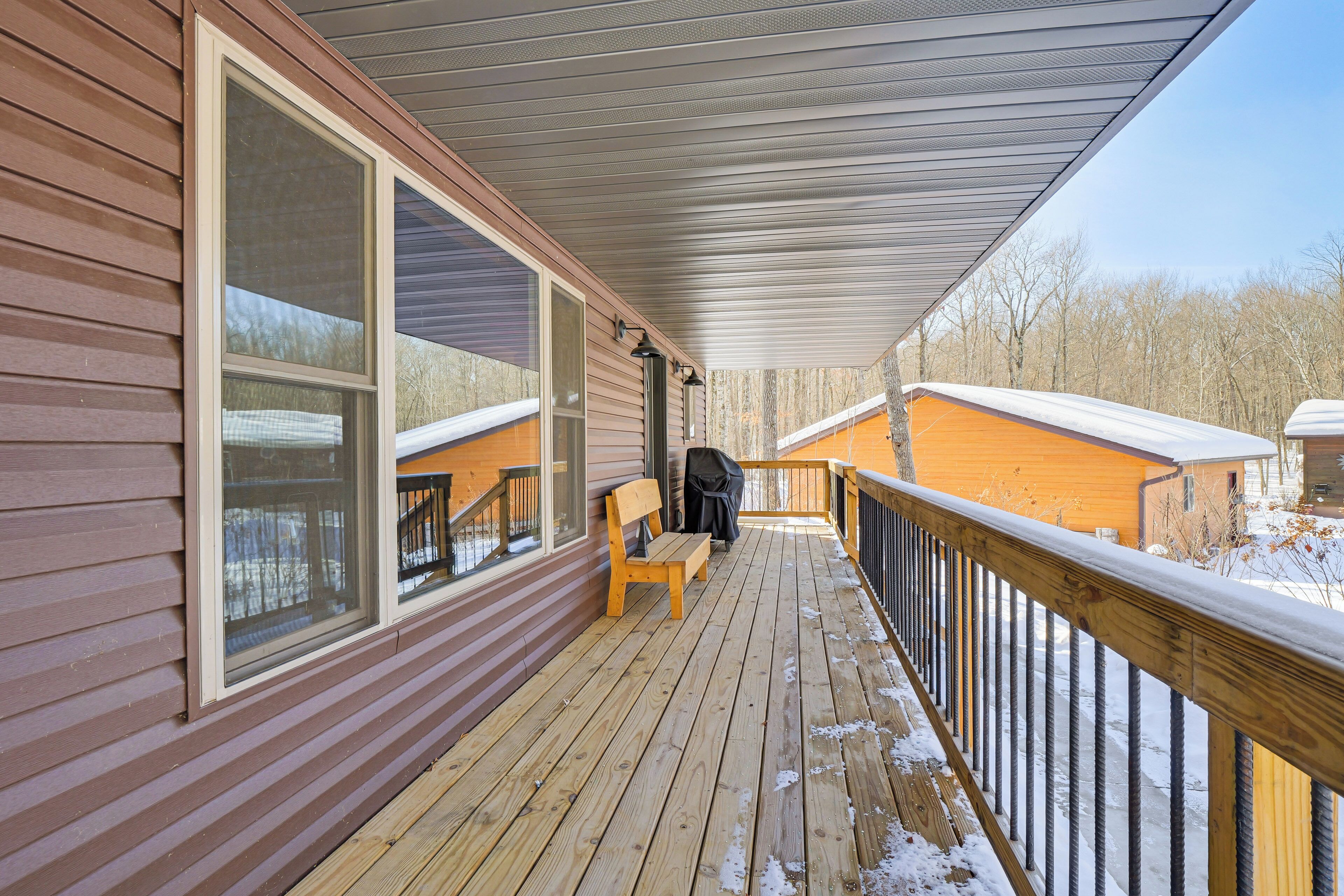 Eine Holzdar Terrasse mit einer Bank und einem überdachten Bereich, mit Blick auf eine verschneite Landschaft.