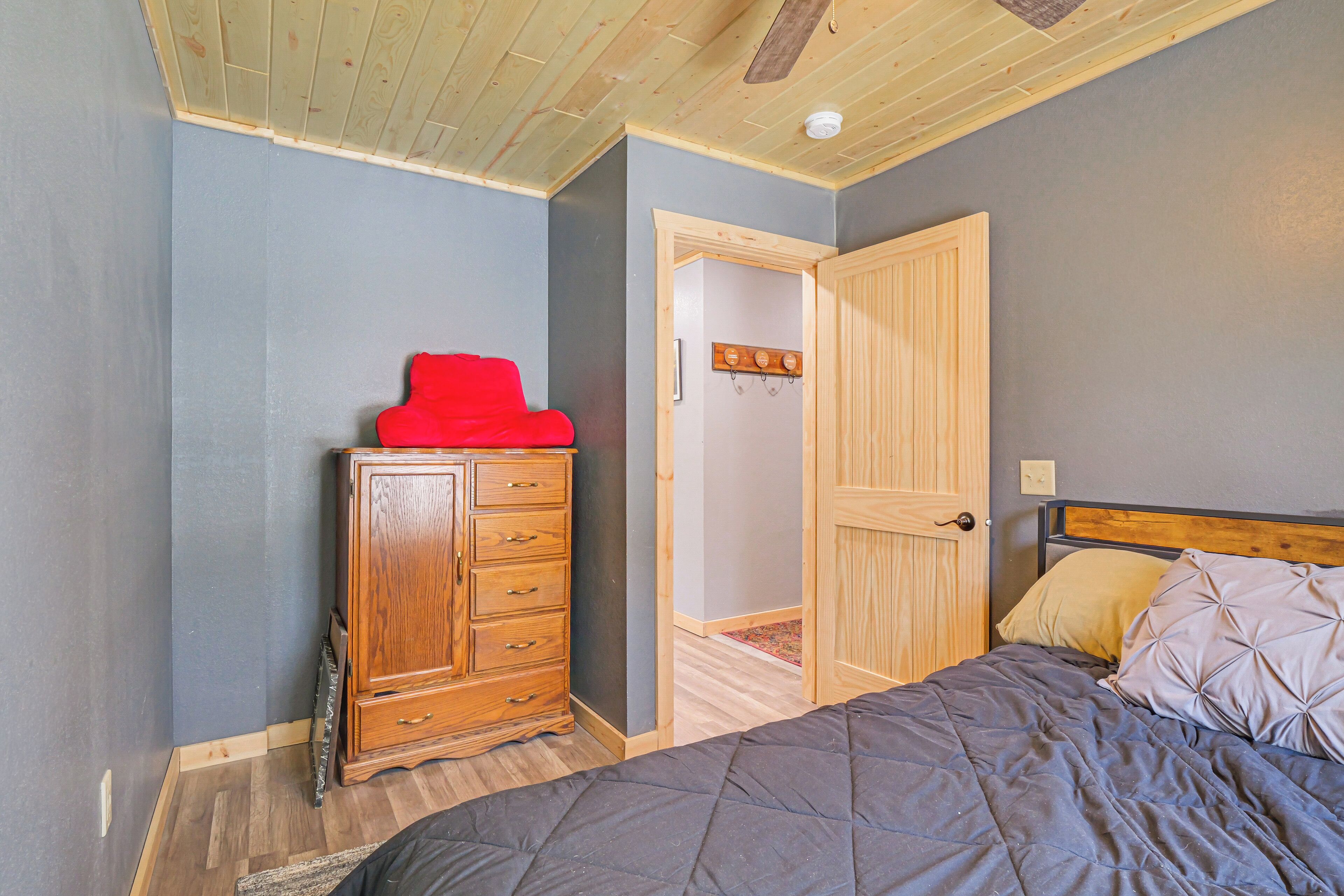A bedroom with a wooden dresser, a bed with a quilted cover, and a door leading to another room.