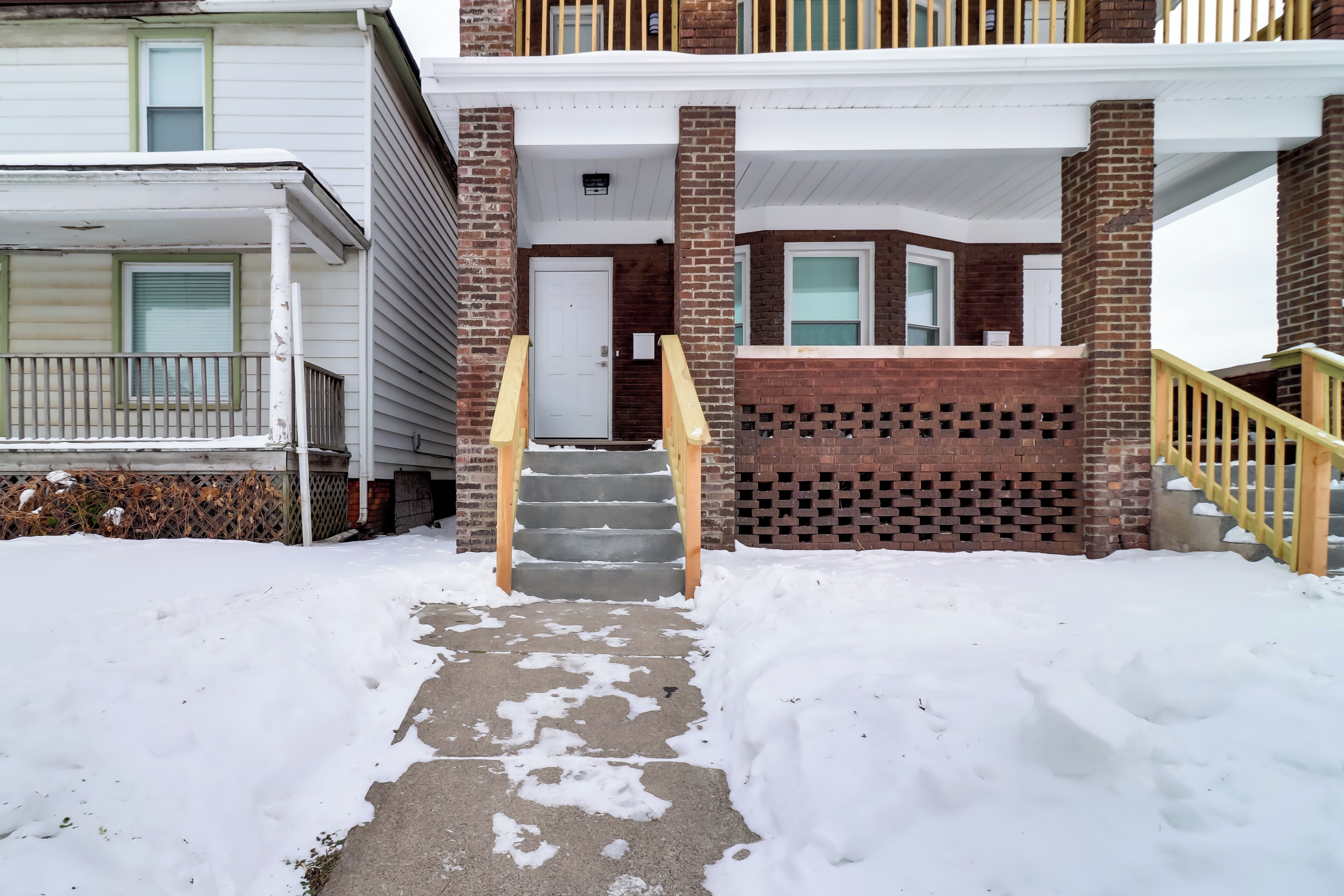 A two-story building with a brick facade, a front porch, and a staircase leading to the entrance.