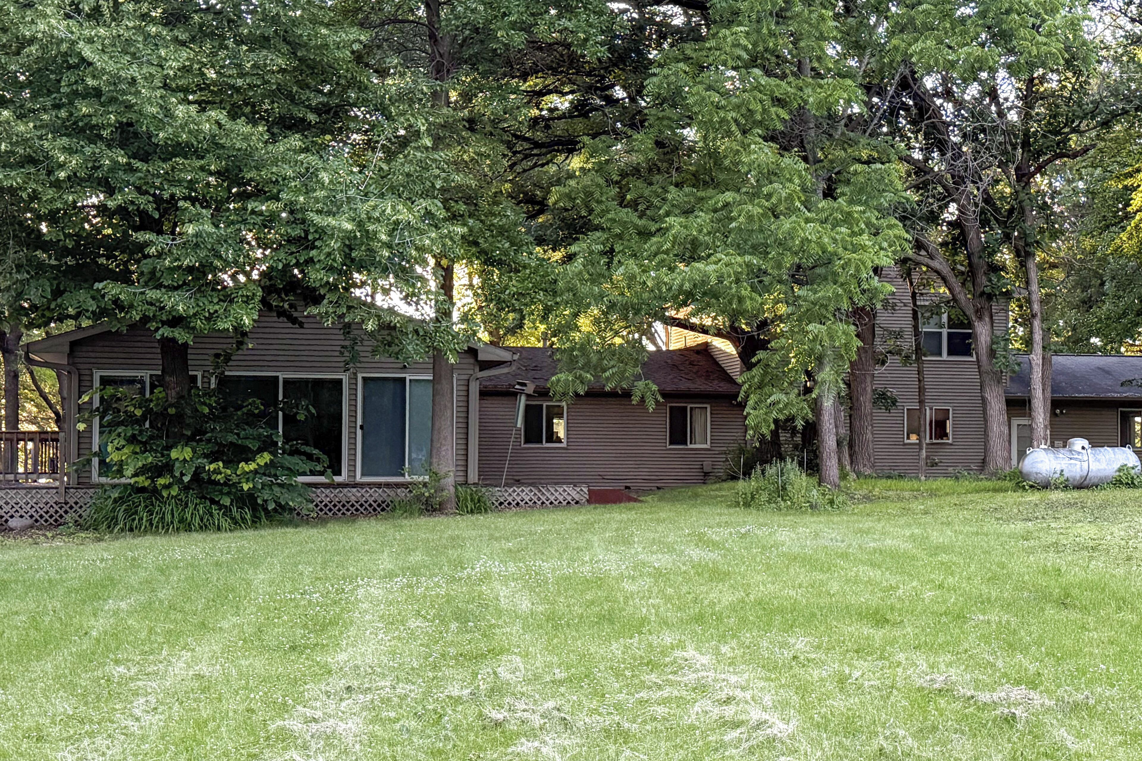 A two-story house with a front porch, surrounded by a grassy yard and trees.