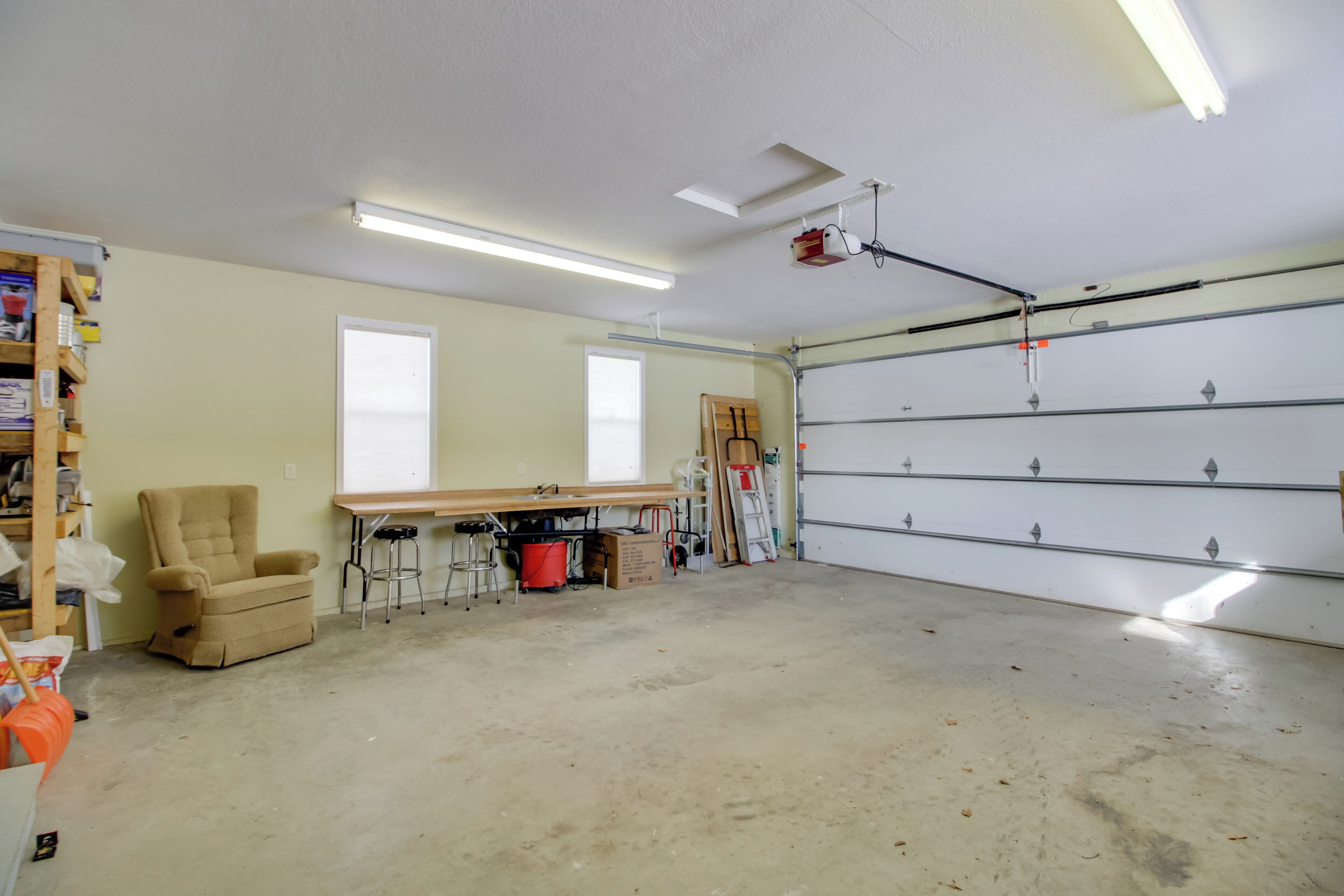 Un garage équipé d’un établi, de chaises et d’une échelle.