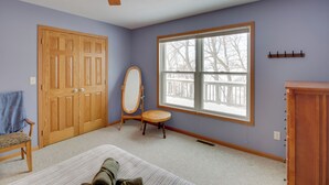 A room with a large window, a ceiling fan, a wooden door, a mirror, and a small table. - Family Nature Haven! Lakefront Pelican Lake Duplex (Ashby)