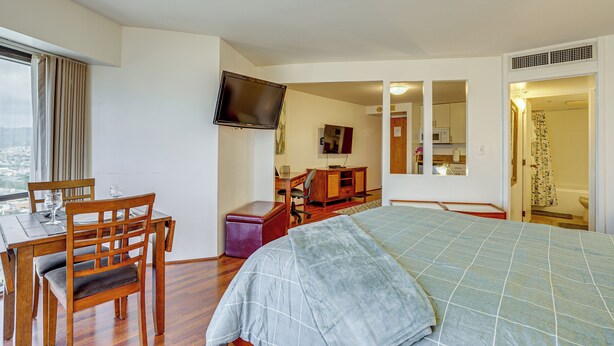 A hotel room with a bed, a desk with a chair, a television, and a bathroom visible through an open door. - Harbor View + Pool Access: Downtown Honolulu Gem! (Honolulu)