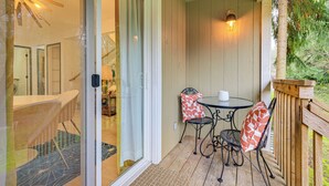 A covered patio with a table and chairs, a sliding glass door leading to an interior space, and a wooden deck with a railing. - Mcm-inspired Decor & Top Location! Tumwater Duplex (Olympia)