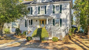 A two-story house with a front porch, a small garden, and a driveway. - Timeless Charm! Family Home Near Belhaven Beach (Belhaven)