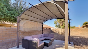 Un patio al aire libre con una zona de estar cubierta, piso de concreto y pared de ladrillo.