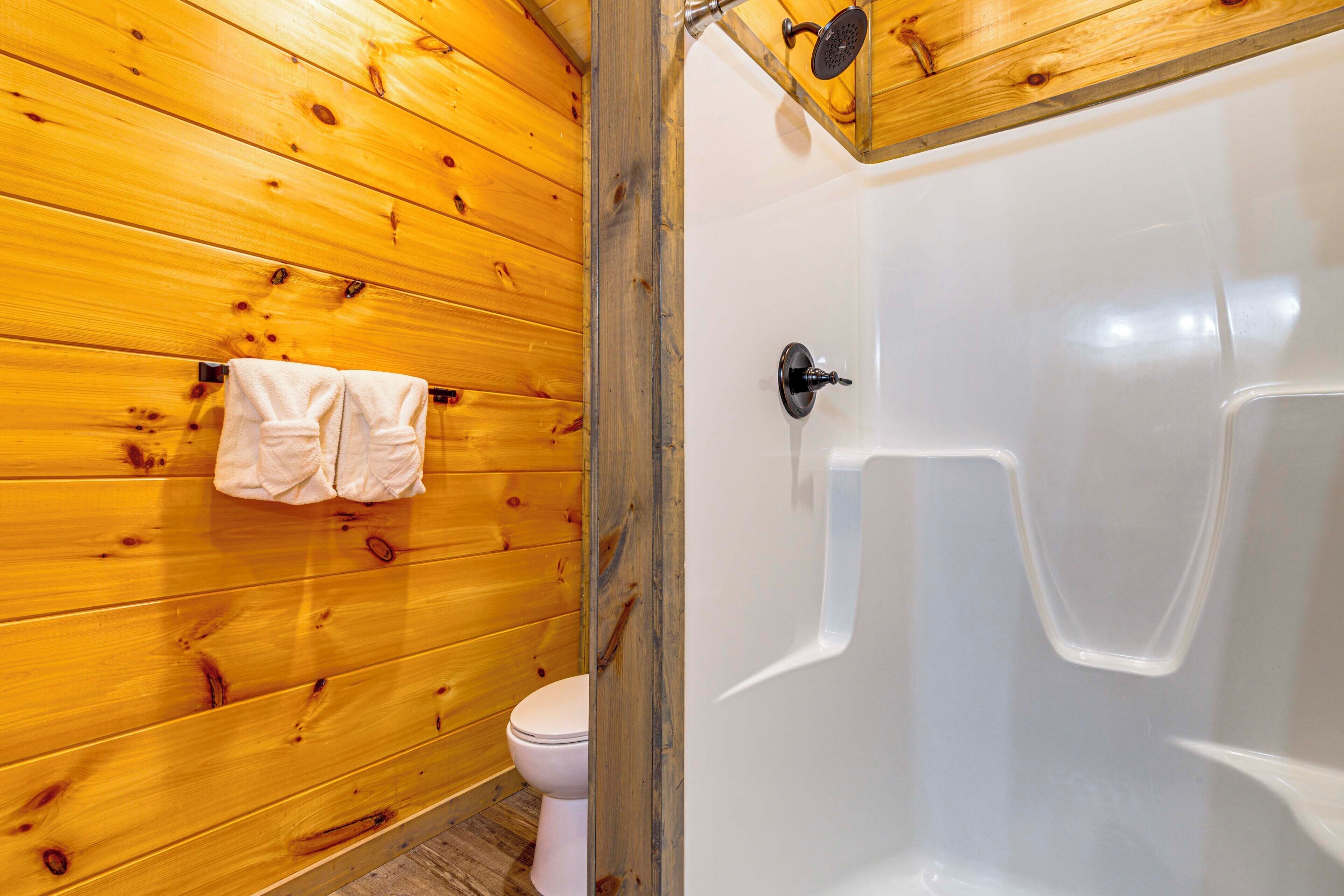 A wooden-paneled bathroom with a white bathtub and a toilet.