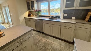 A modern kitchen with a large window, a dishwasher, and a view of the outdoors.