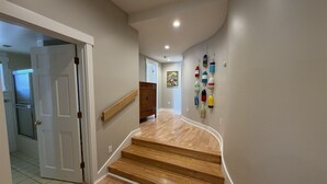 A hallway with wooden stairs, a white door, and a wall with colorful buoys.
