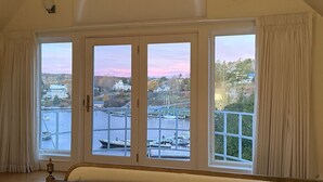 A bedroom with a large window overlooking a marina and a river.