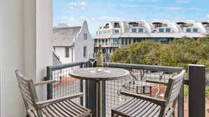 Ein Balkon mit zwei Holzstühlen, einem runden Tisch und einer Weinflasche.