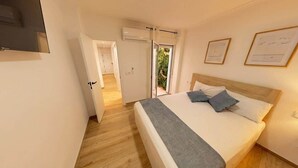 A bedroom with a bed, a bedside table, a mirror, and a door leading to a balcony. - Modern apartment in the center of Tavernes (Tavernes de la Valldigna)