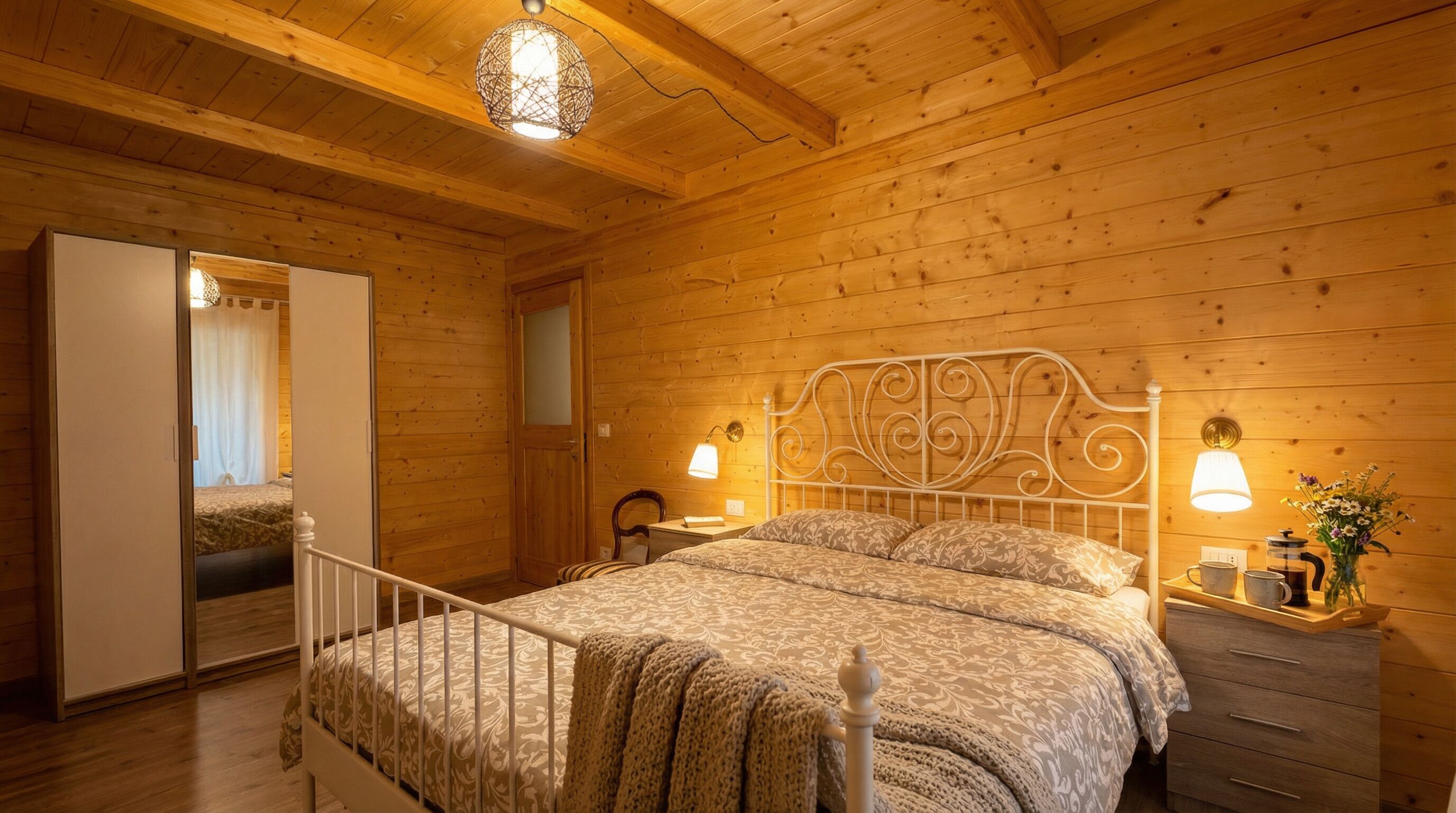 A wooden-paneled room with a bed, bedside lamps, a nightstand, and a wardrobe.