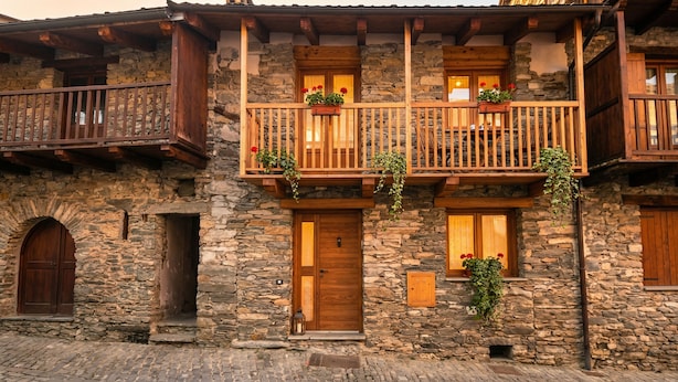 Un bâtiment en pierre doté de balcons en bois, d’une porte en bois et d’une arche en pierre.