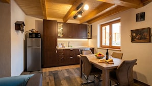 Une cuisine compacte avec des meubles en bois, un réfrigérateur, une table à manger avec des chaises et une fenêtre donnant sur un beau paysage.