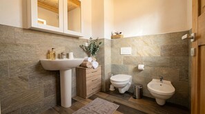 A bathroom with a sink, toilet, bidet, and wooden cabinet. - Cozy Alpine House · Becetto, Valle Varaita · WiFi & Private Parking (Becetto)