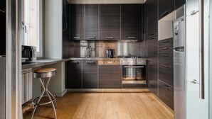 Een moderne keuken met donkere kastjes, roestvrijstalen apparatuur en een houten vloer.