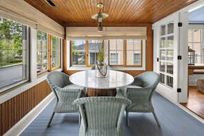 A room with a round table, wicker chairs, a potted plant, and large windows. - NEW TO VRBO: 9 BR-7.5 BA RENOVOTED REHOBOTH BEAUTY-STEPS TO SAND-6 NEW CASTLE (Rehoboth Beach)