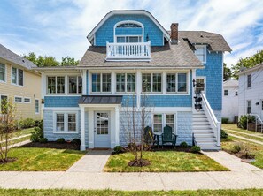 A two-story house with a front porch, a staircase, and a small garden area. - NEW TO VRBO: 9 BR-7.5 BA RENOVOTED REHOBOTH BEAUTY-STEPS TO SAND-6 NEW CASTLE (Rehoboth Beach)