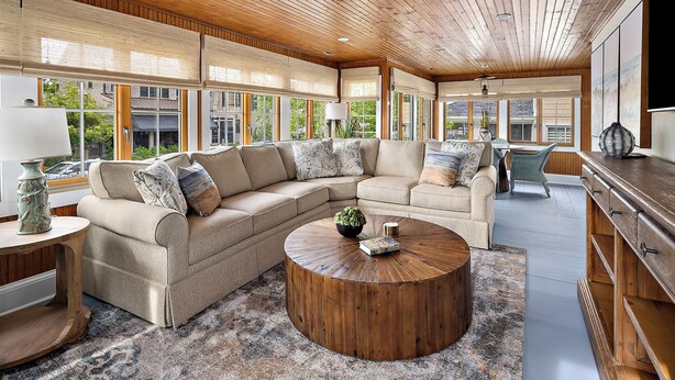 A spacious living room with a large sectional sofa, a round coffee table, and a wooden ceiling.