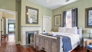 A bedroom with a wooden bed, a fireplace, and green walls. - Savannah Home, Walkable to Forsyth, Historic (Savannah)