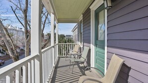 A covered porch with a railing, two chairs, and a door with a green trim. - Savannah Home, Walkable to Forsyth, Historic (Savannah)