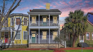 A two-story house with a balcony, a red door, and a small front yard with a tree. - Savannah Home, Walkable to Forsyth, Historic (Savannah)