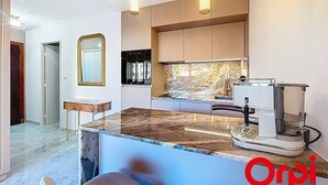 A modern kitchen with a marble countertop, a coffee machine, and a view of the city through the window. - Renovated Apartment with Terrace and Parking in Menton (Menton)