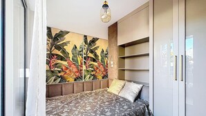 A bedroom with a bed, a large wall mural, a wardrobe, and a hanging light fixture. - Renovated Apartment with Terrace and Parking in Menton (Menton)