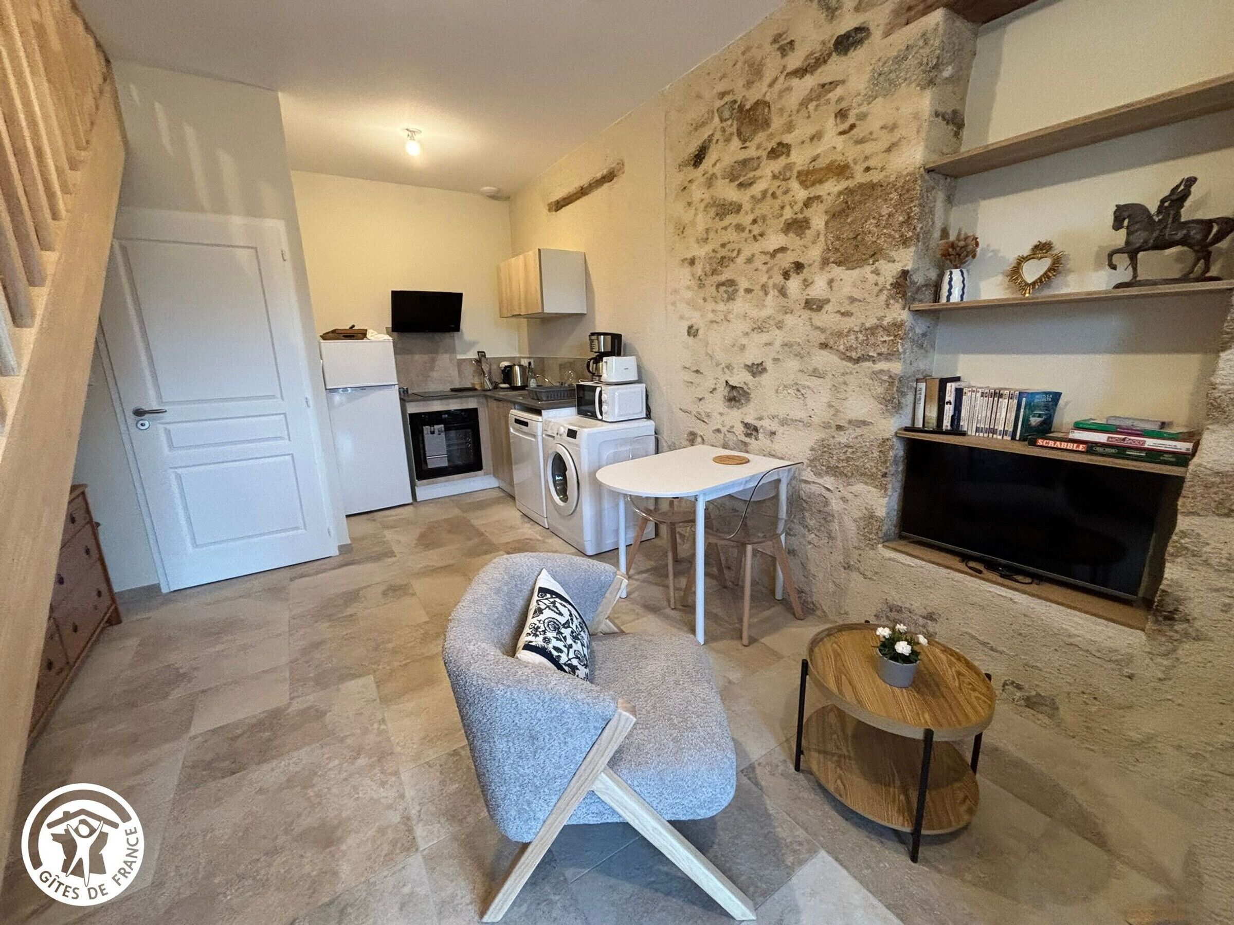 A compact living space with a kitchenette, a dining area, and a seating area with a small round table and a sofa.