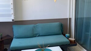 A teal sofa in a room with a wall clock, a hanging pendant light, and a potted plant. - Air-Conditioned Apartment with Parking in Saint-Gilles (Saint-Gilles les Bains)