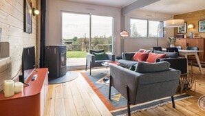 Ein modernes Wohnzimmer mit Kamin, Essbereich und großen Schiebegläsern zum Garten.